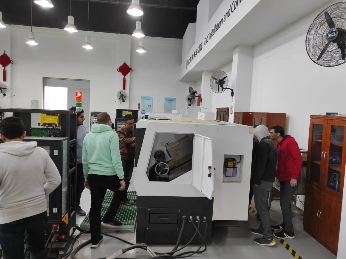 A group of people standing around a machine Description automatically generated with medium confidence