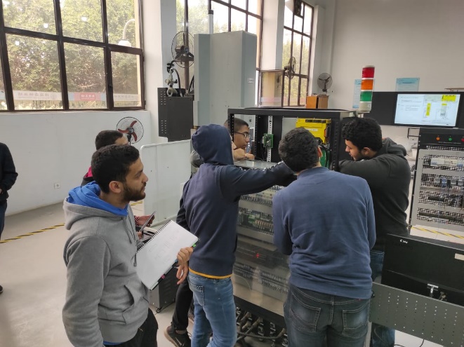 A group of people standing around a machine Description automatically generated with medium confidence