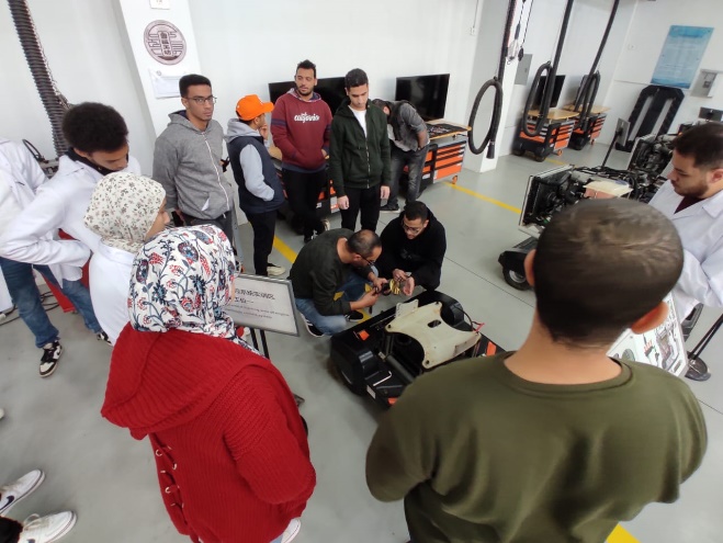 A group of people standing around a machine Description automatically generated with medium confidence